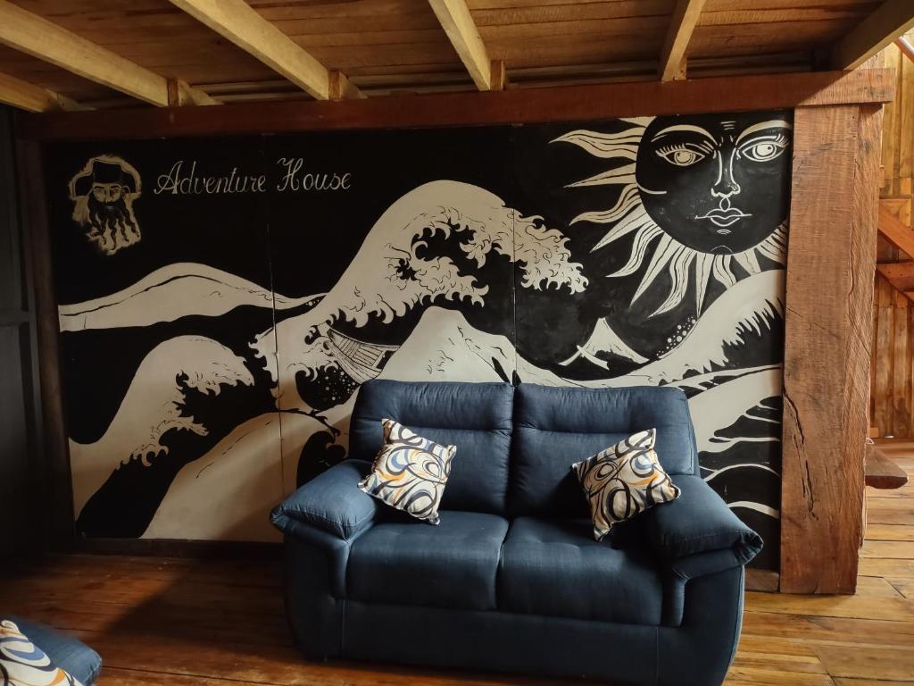 - un salon avec un canapé bleu devant une fresque dans l'établissement Barba Negra Adventure House, à Sierpe