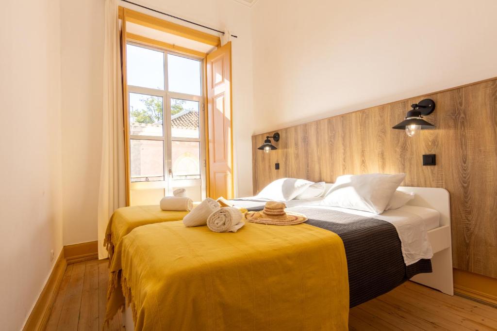 1 dormitorio con 2 camas con sábanas amarillas y ventana en GrowIN Digital Nomads, en Faro