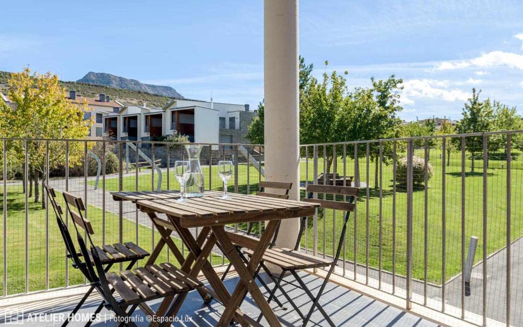 - Balcón con mesa de madera y 2 sillas en Duplex Las Margas Vista Montañas, en Sabiñánigo