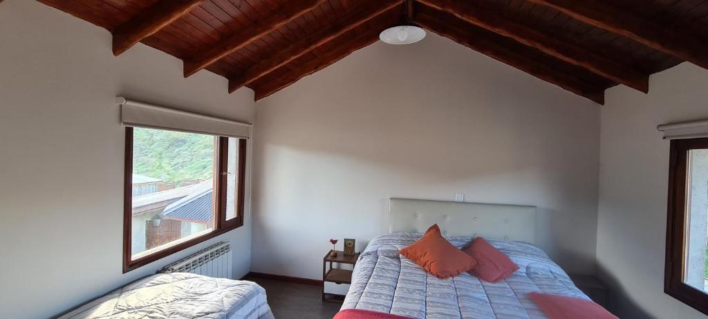 1 dormitorio con 1 cama con almohadas de color naranja y ventana en Kuntur Apart en El Chaltén