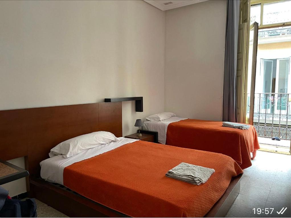 Habitación de hotel con 2 camas y ventana en Hostal “ INFANTAS”, en Madrid