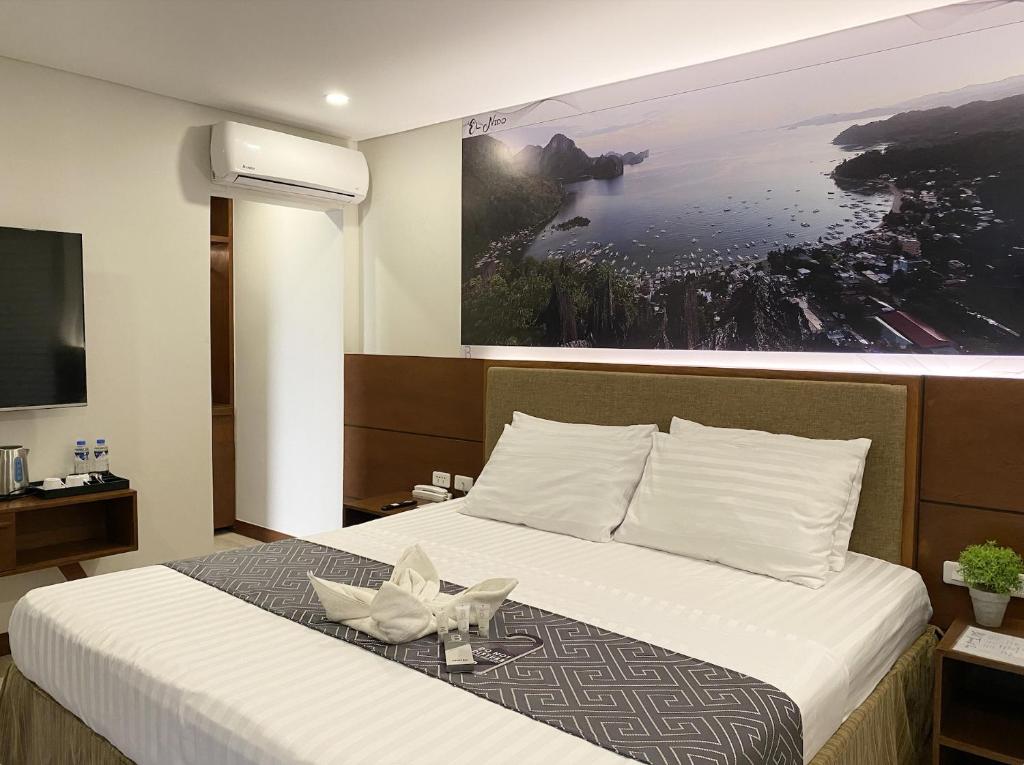 una habitación de hotel con una cama con una foto en la pared en Bill Tourist Inn, en El Nido