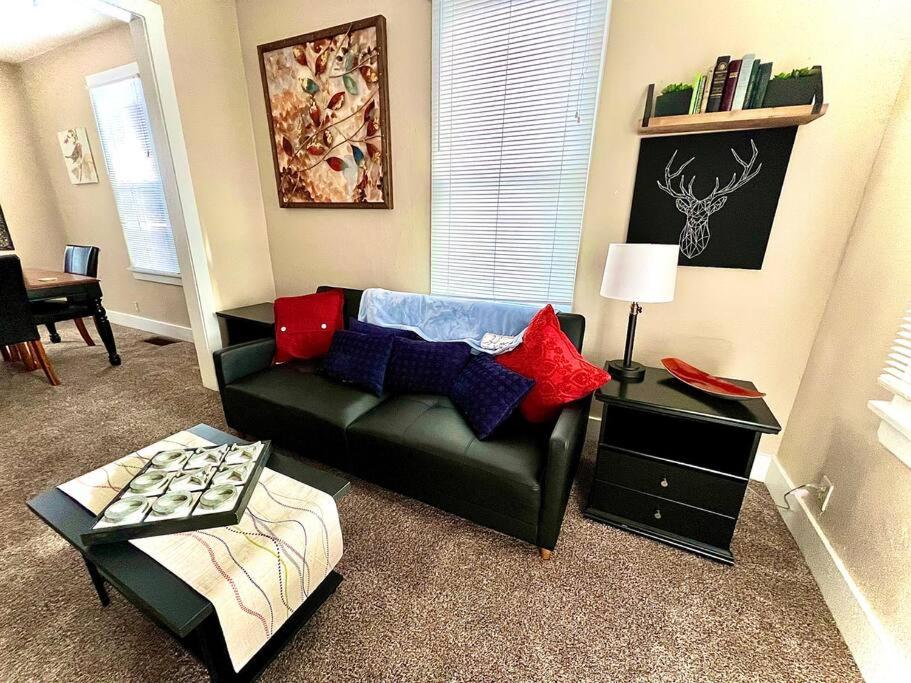 una sala de estar con un sofá negro con almohadas rojas y azules en Cozy cottage in the heart of the big city- dog friendly en Billings