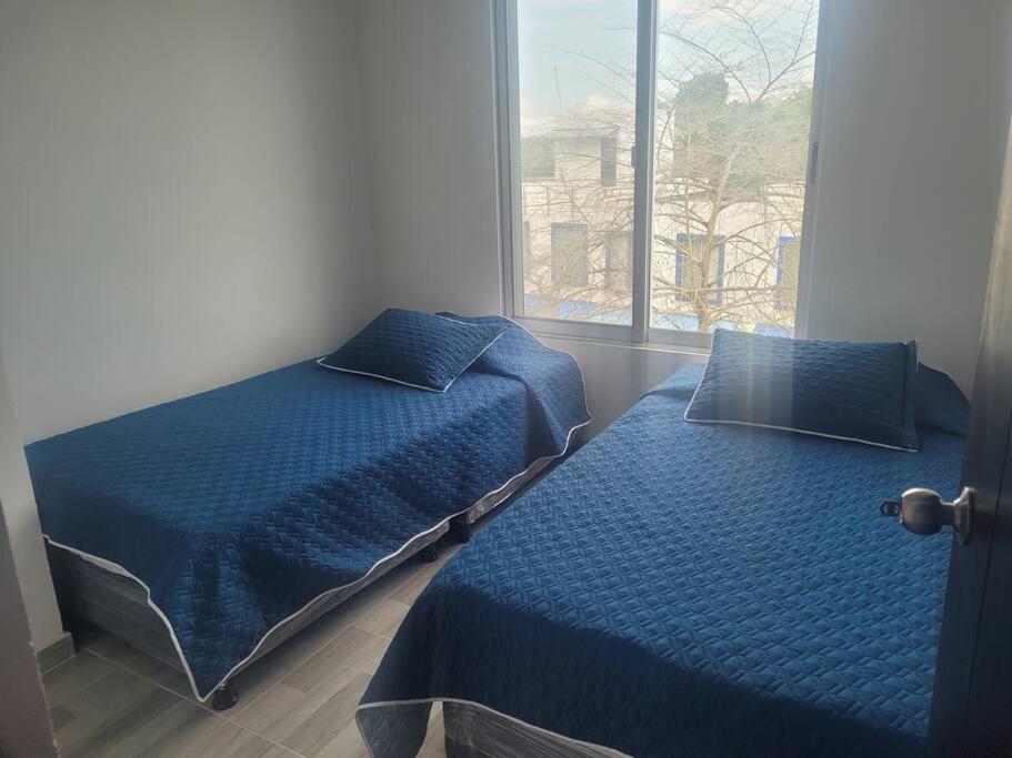 - une chambre avec 2 lits et une fenêtre dans l'établissement Casa Vacacional en Carmen de Apicala, Colombia, à Carmen de Apicalá