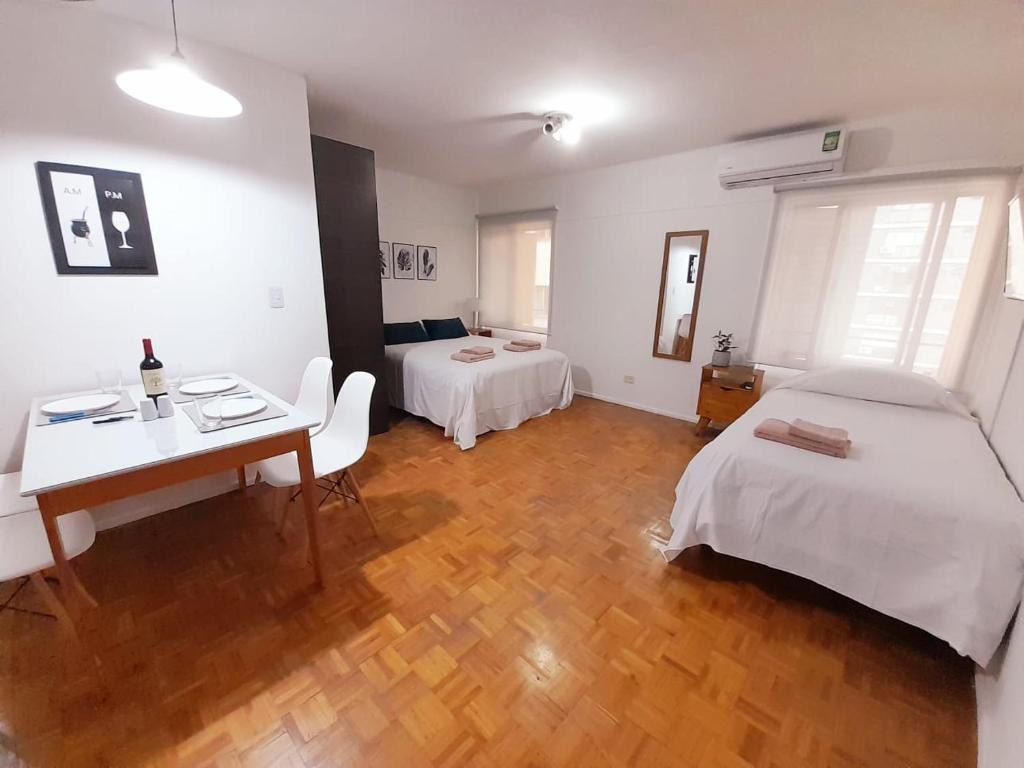 a room with two beds and a table and a desk at Mendoza Apartment in Mendoza