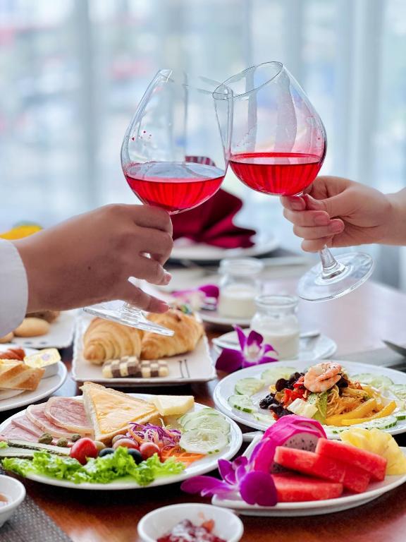 A staged dining scene with two glasses of red wine and a selection of plated food.