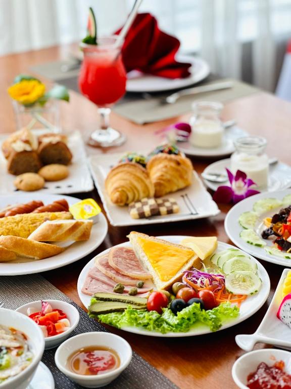 A close-up of pastries, cold cuts, bread, salad and fruit on a breakfast table.