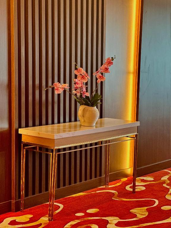 A decorative console table with a flower arrangement in a carpeted hotel corridor.