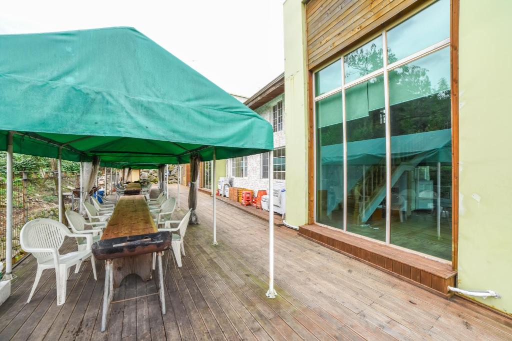 una terrazza in legno con tavolo e ombrellone verde di Full Pension a Gimhae