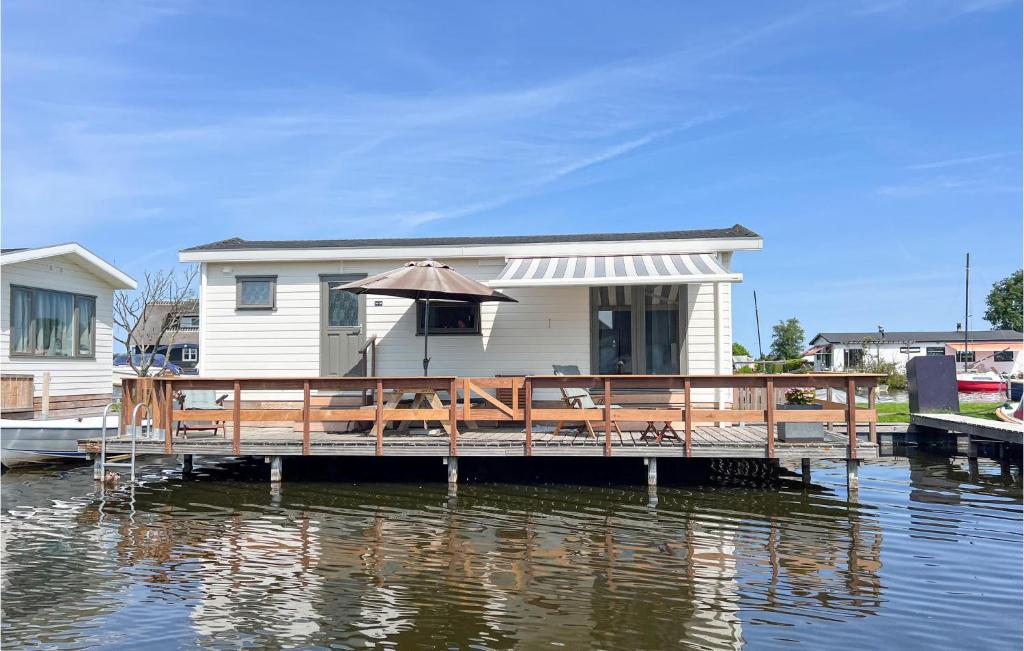 une maison avec un parasol sur un quai sur l'eau dans l'établissement 2 Bedroom Pet Friendly Home In Breukelen, à Breukelen