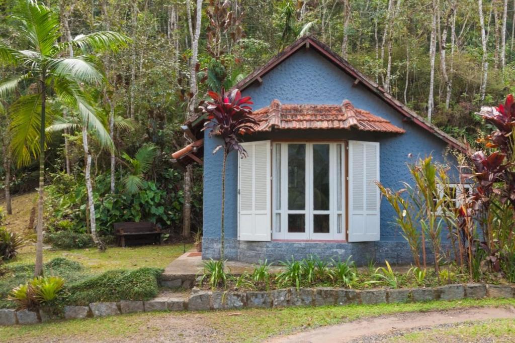 a blue house with a window in a forest at Chalé Gaia - Itatiaia in Itatiaia