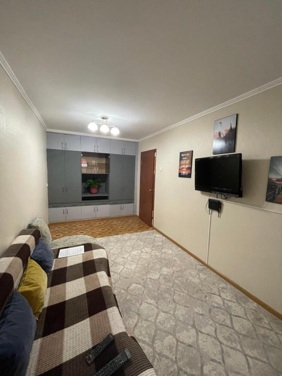 ein Wohnzimmer mit einem Sofa und einem Flachbild-TV in der Unterkunft 2-х комнатная Ауезова in Öskemen