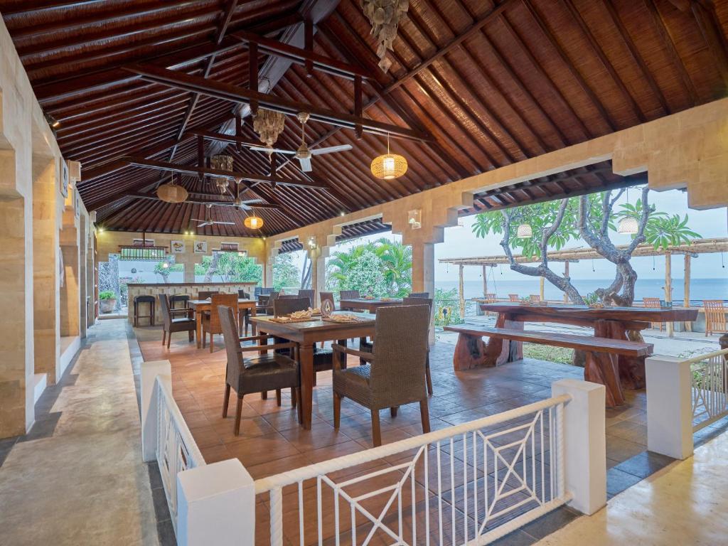 a restaurant with tables and chairs and a view of the ocean at Anda Amed Villas & Spa in Amed