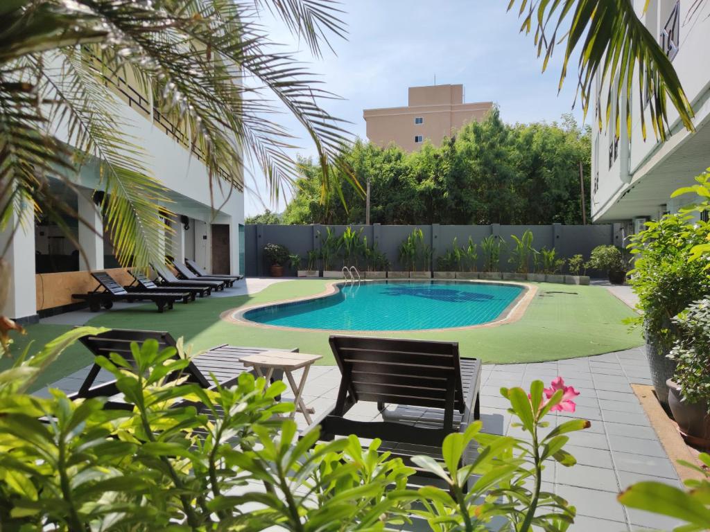 un cortile con piscina e sedie e un edificio di The Chanthong Residence and Hotel Pattaya a Pattaya Sud