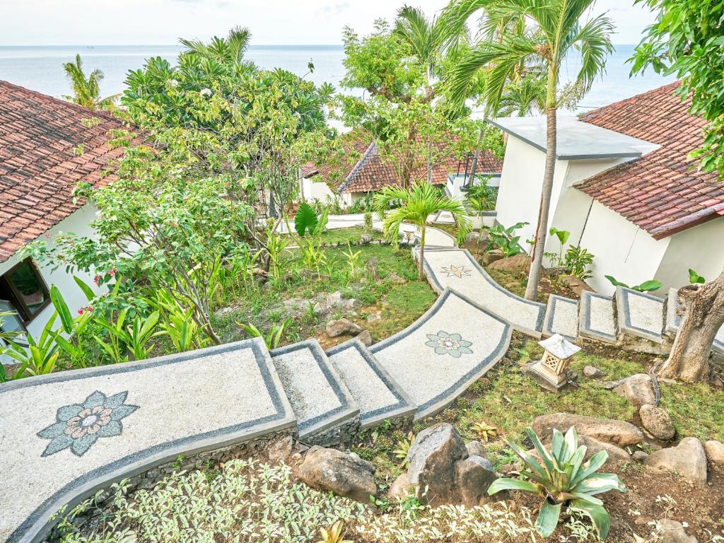 a garden with benches and the ocean in the background at Anda Amed Villas & Spa in Amed