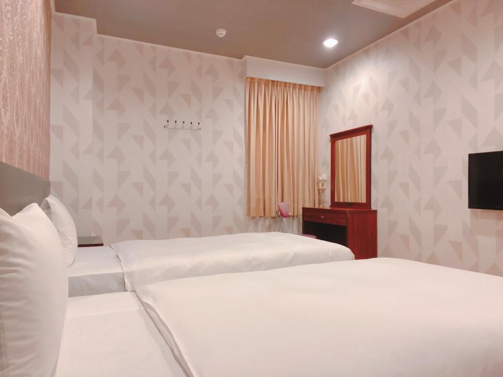 a bedroom with two beds and a flat screen tv at Centre Hotel in Kaohsiung