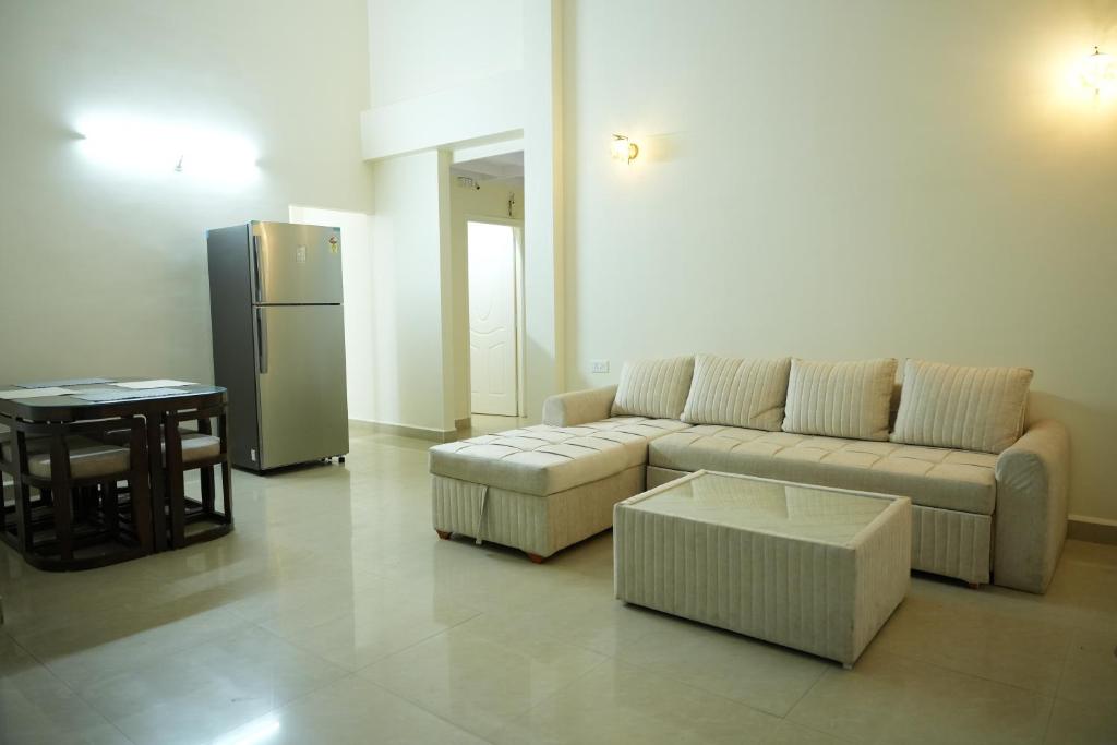 a living room with a couch and a table and a refrigerator at Shri Mahamaya in Panaji