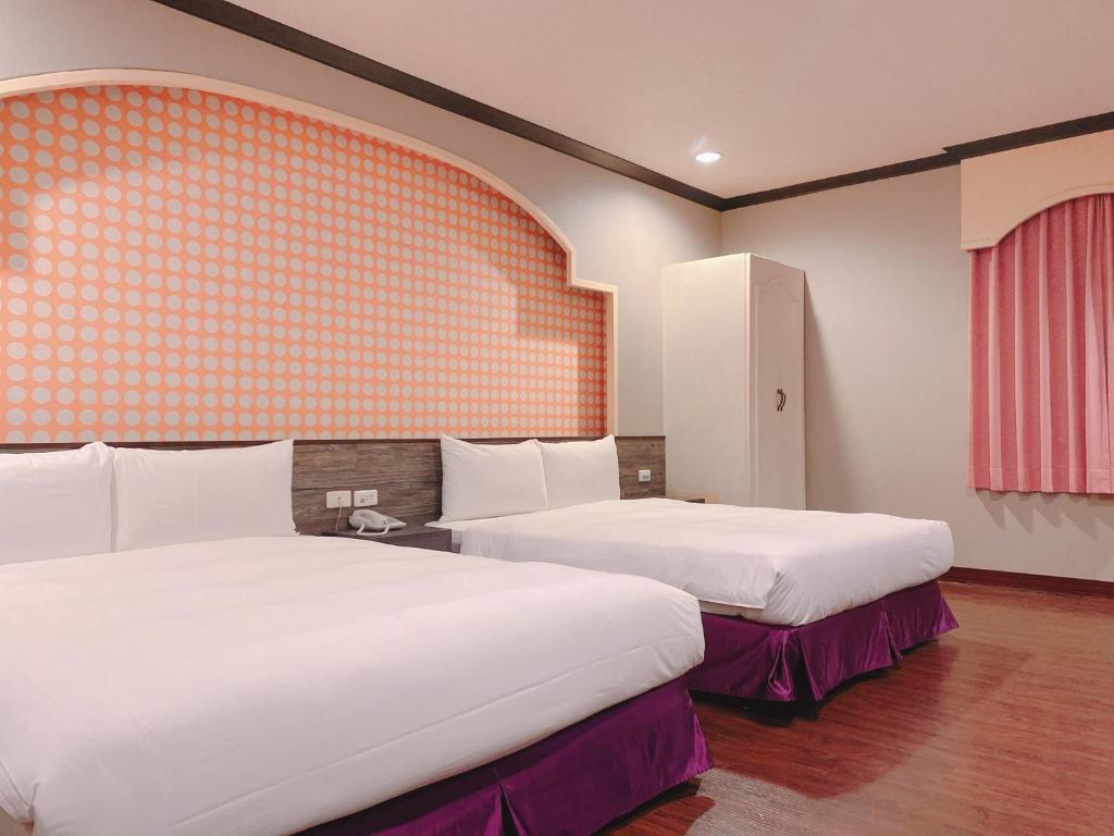 a hotel room with two beds and an orange wall at Centre Hotel in Kaohsiung