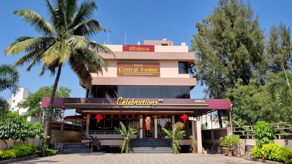 a building with a palm tree in front of it at Hotel Central Avenue in Sangli