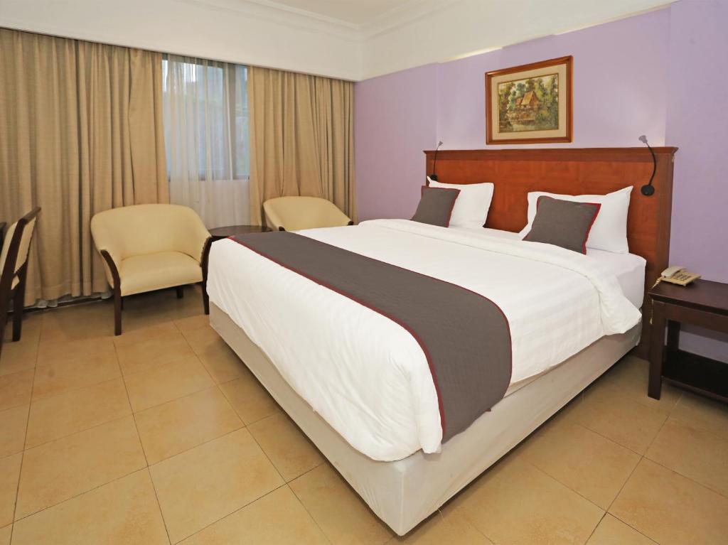 una camera con un grande letto e un tavolo con sedie di Super OYO Collection O 91898 Series Hotel Kuningan a Giacarta