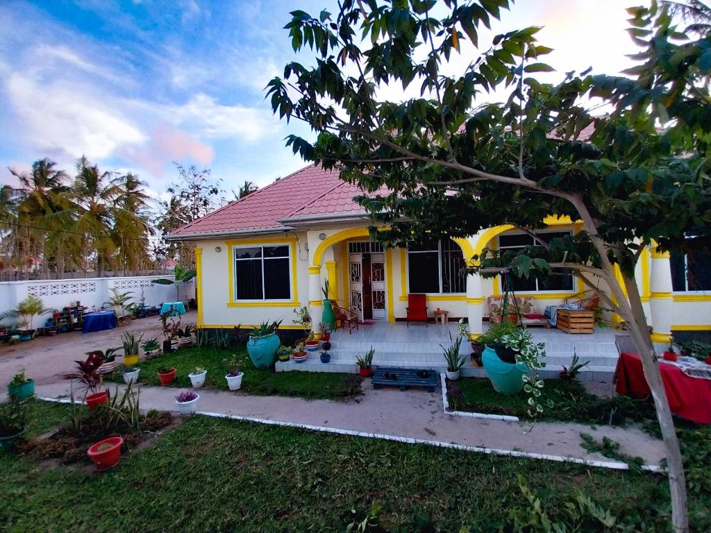 una casa amarilla con un árbol en el patio en L&J Modern Backpackers Kigamboni Beach House en Dar es Salaam