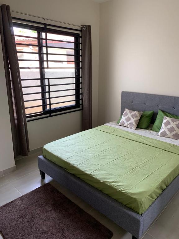 a bedroom with a bed with a green bedspread and a window at Casa Alta Gracia in Paramaribo