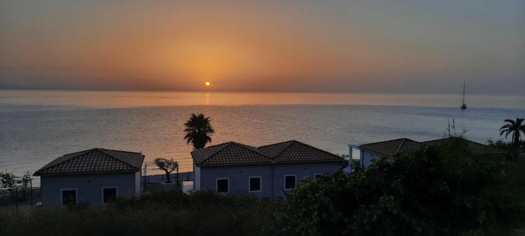 un tramonto sull'oceano con case e palme di Galleria 38 a Soverato Marina