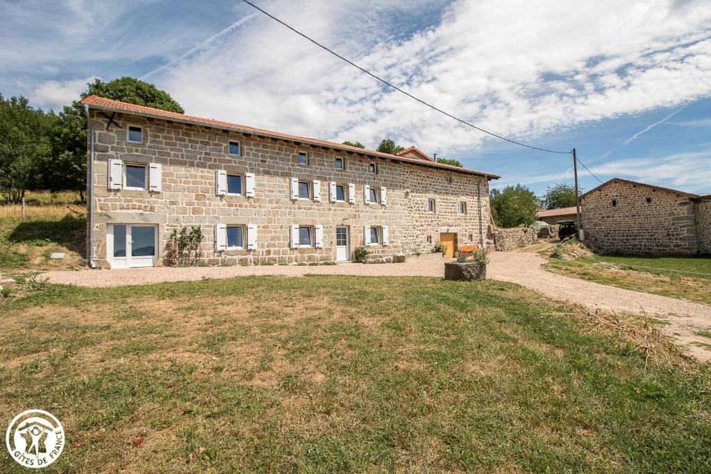 un gran edificio de piedra con un campo de césped delante de él en LA VIE D'ANCE, en Saint-Anthème