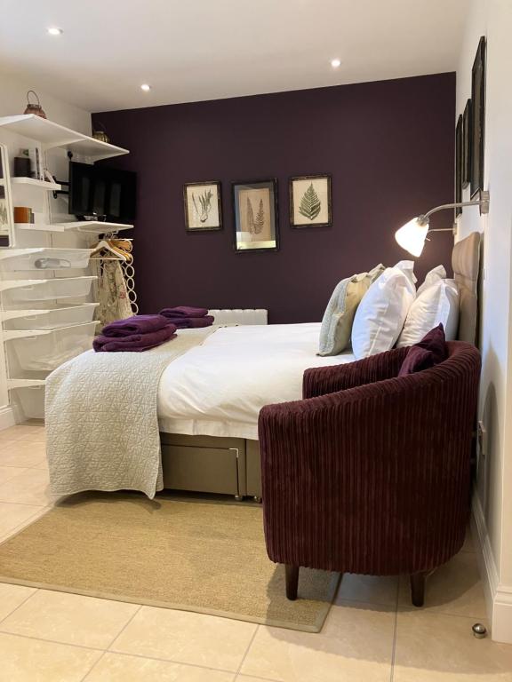 a bedroom with a large bed and a chair at The Burrow in Wellesbourne Hastings