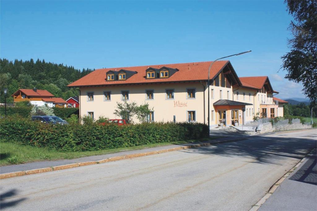 a large white house with a red roof on a street at Witikohof in Haidmühle