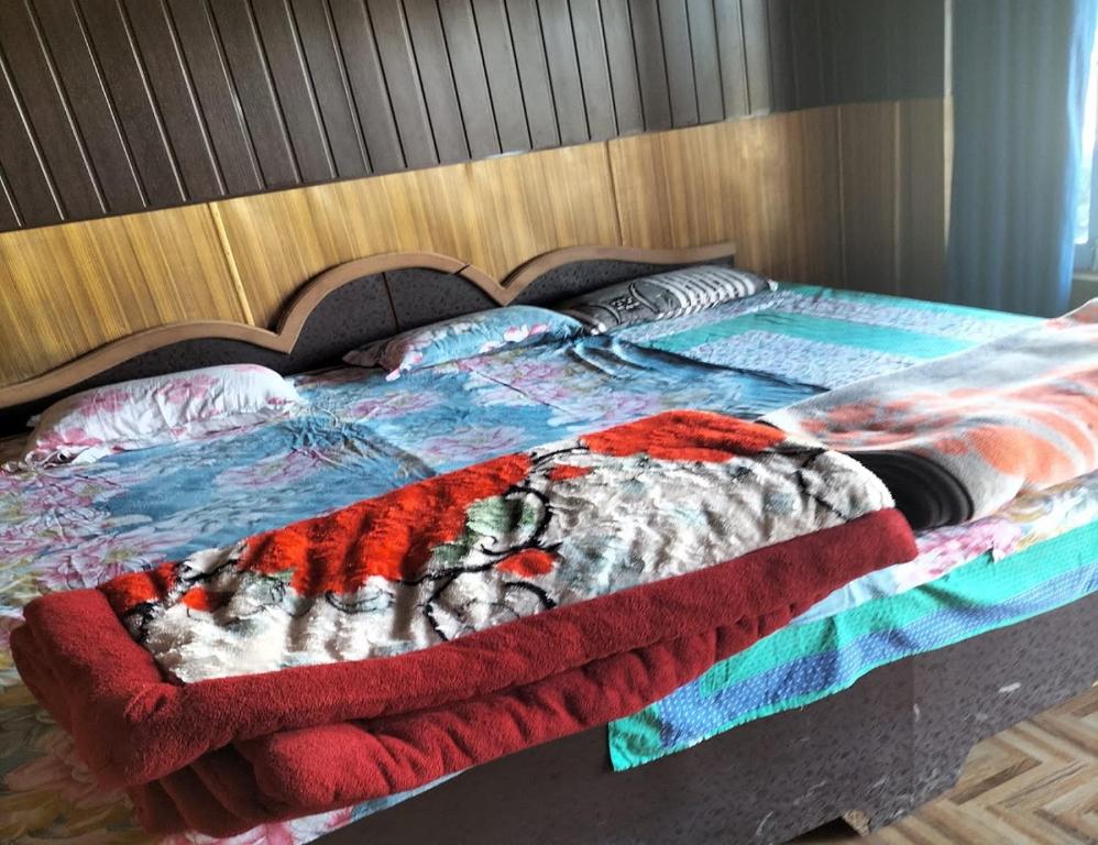 a bed with a colorful comforter and pillows on it at Aangan Resort, Bageshwar in Bāgeshwar