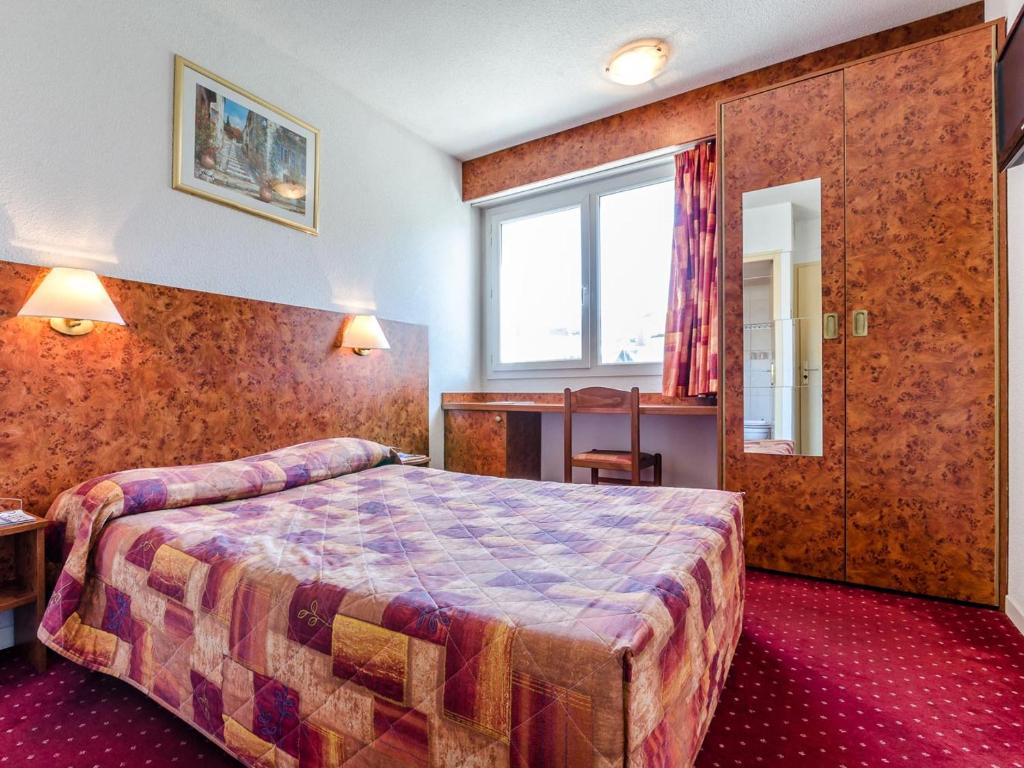 ルルドにあるHôtel Agenaのベッドと窓が備わるホテルルーム