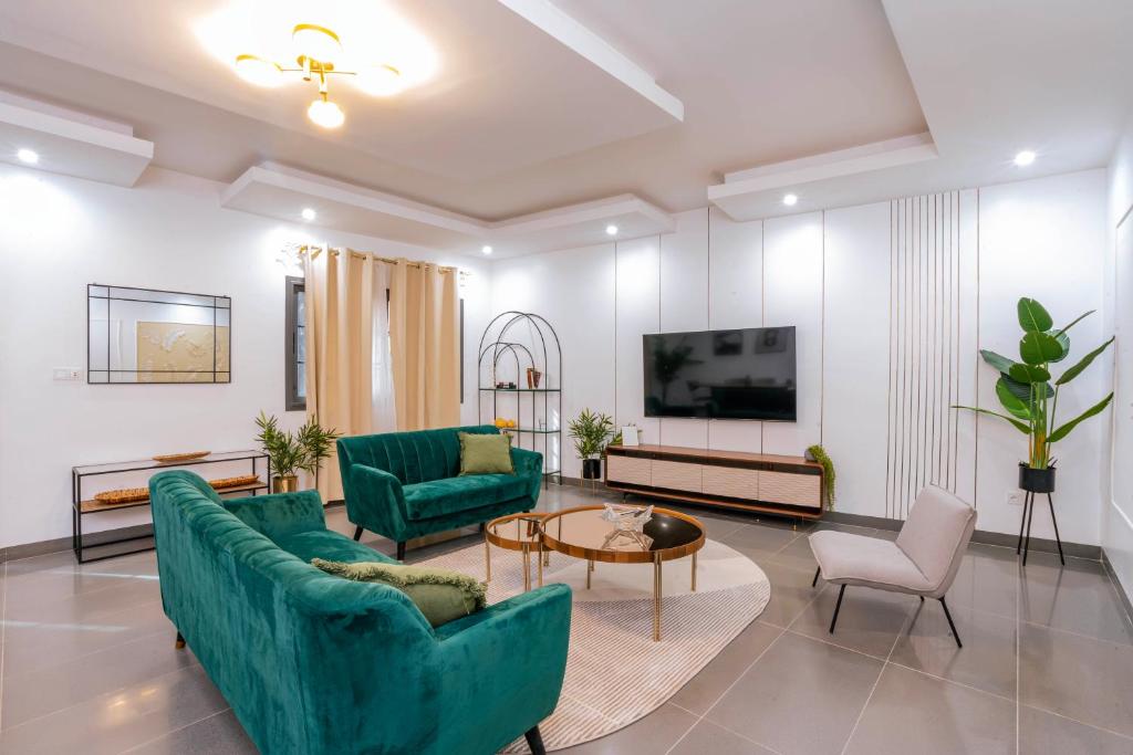 a living room with two green couches and a table at Lighthouse Signature Suites in Dakar