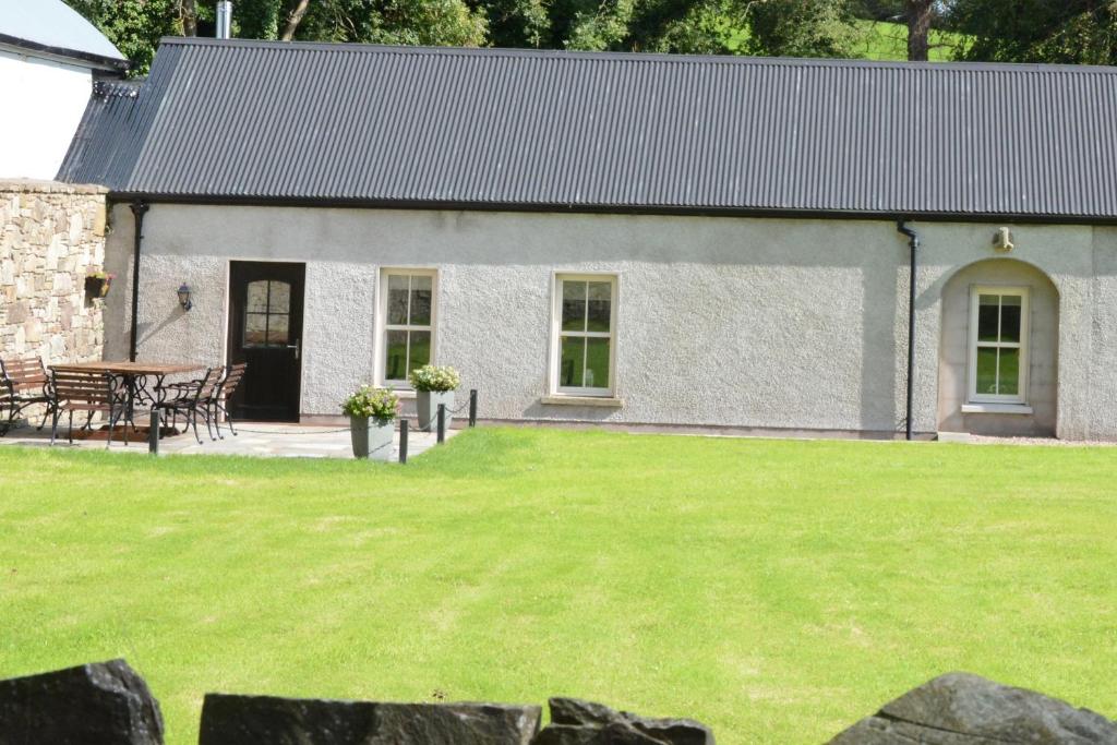 una casa de campo con un césped verde delante de ella en Rectory Cottage. Close to Enniskillen and lakes., en Enniskillen
