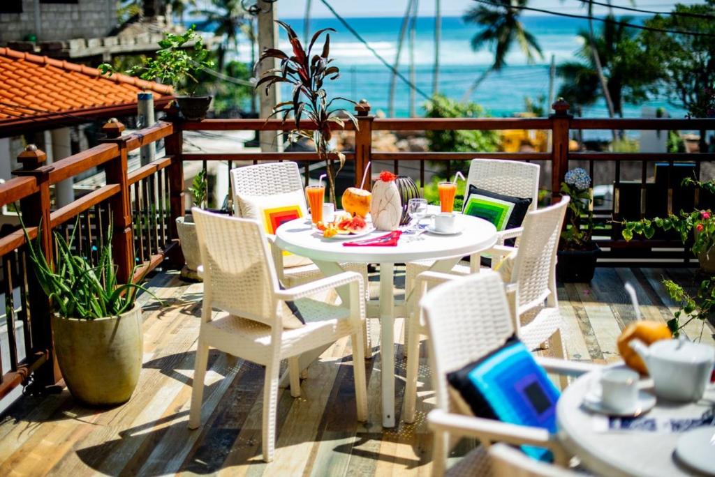 uma mesa branca e cadeiras numa varanda com o oceano em Glamour Mirissa em Mirissa