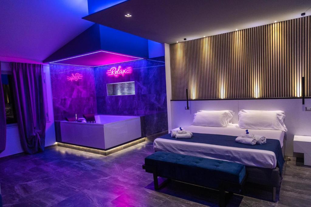 a bedroom with a bed and a tub with purple lighting at B&B Del Centro e SPA in Partinico