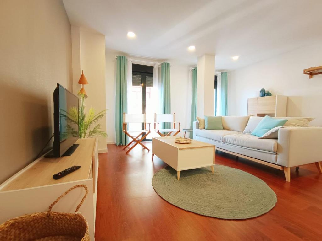 a living room with a couch and a tv at Expoholidays - Apartamento Rueda Lopez (7ºB) in Almería