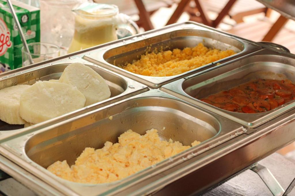 a buffet with three trays of food on a table at Pousada Vila do Penedo in Penedo