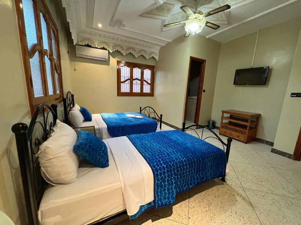 a bedroom with two beds with blue and white sheets at Riad Perlamazigh in Zagora