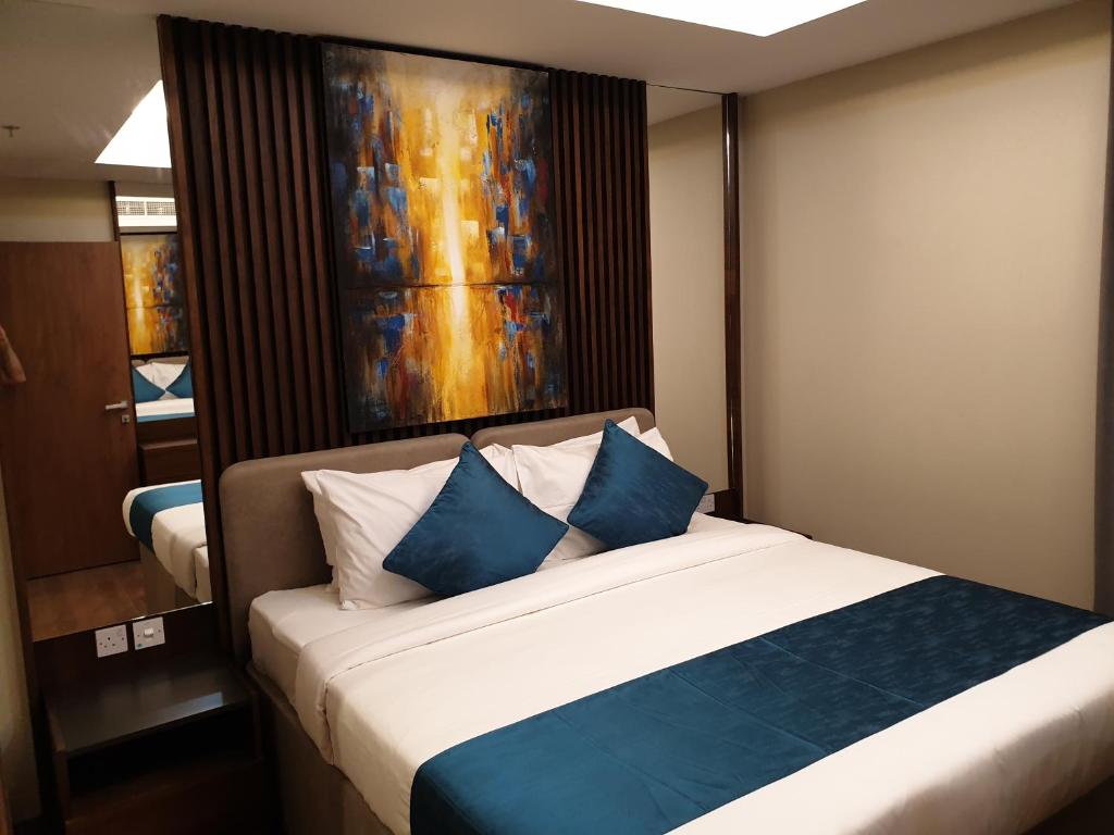 1 dormitorio con 1 cama con almohadas azules y blancas en Terminal Inn Al Mansoura en Doha