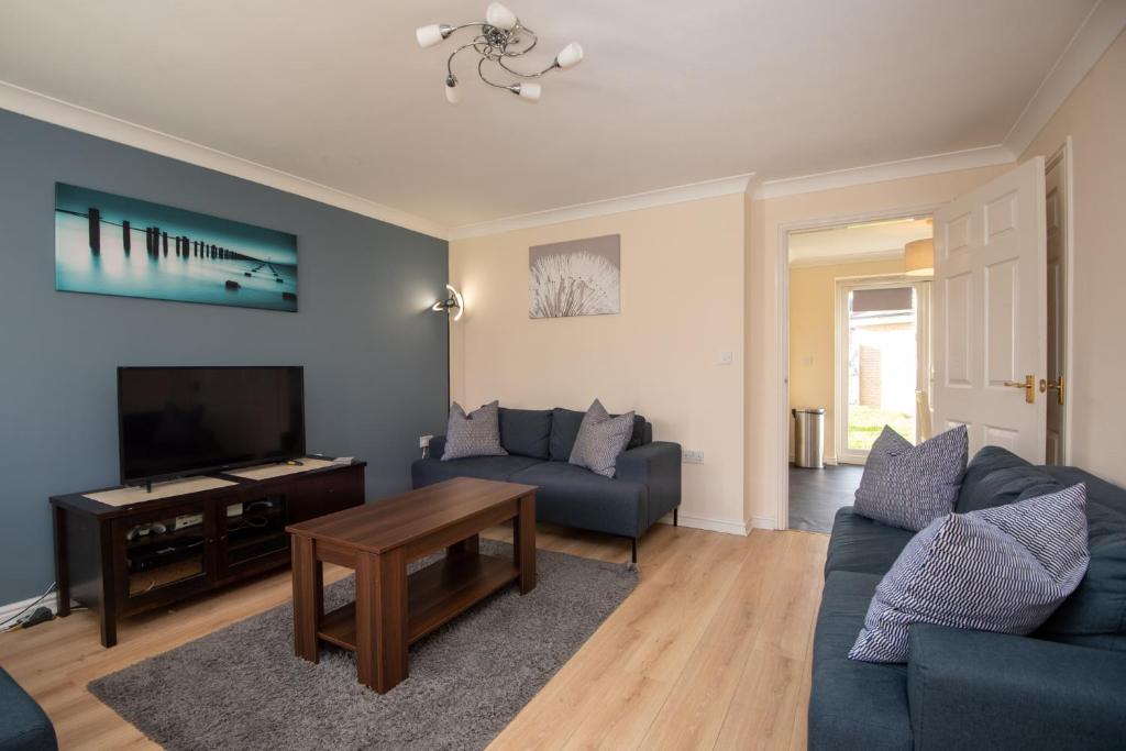 a living room with a blue couch and a tv at Hillbrook in Thornaby on Tees