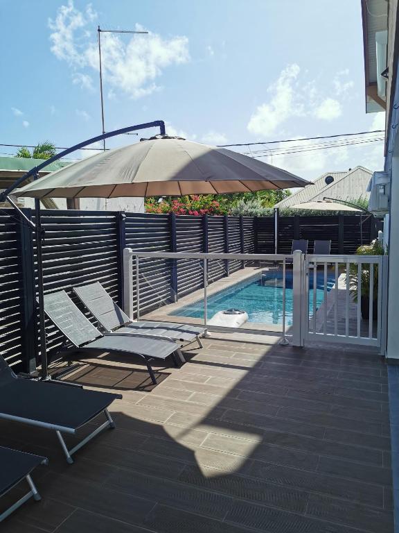 a patio with chairs and an umbrella next to a swimming pool at L'améthyste in Saint-François