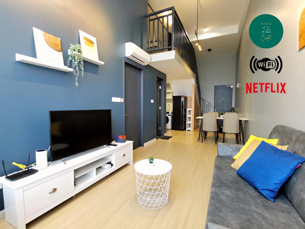 a living room with a couch and a tv at Cozy Loft By Hauzcinta @Sunway Grid in Kampong Pendas