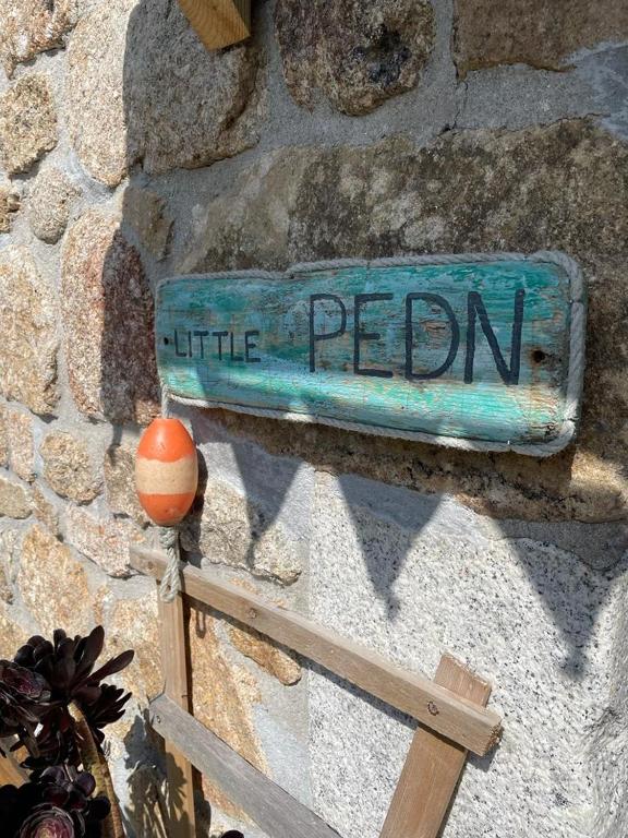 a blue sign on the side of a stone wall at Little Pedn in Penzance
