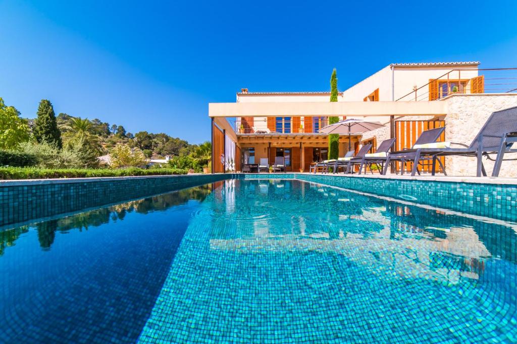 uma piscina com água azul em frente a um edifício em Ideal Property Mallorca - Sa Vinyeta em Selva