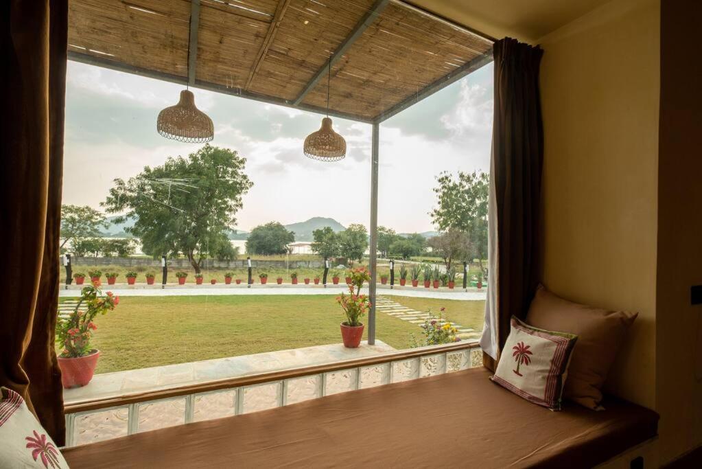 a window in a room with a view of a field at 1br Cottage with Pool - Eagle's Nest by Roamhome in Udaipur