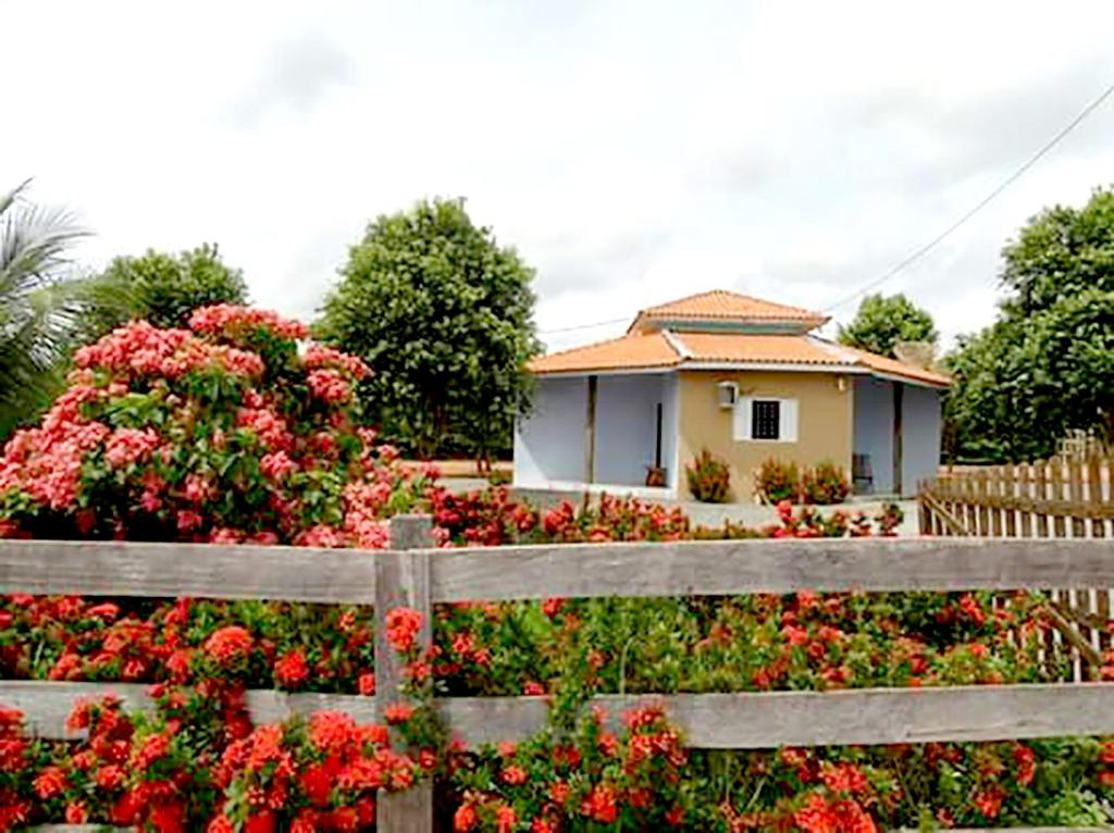 uma casa atrás de uma cerca de madeira com flores em Pousada Canto das Araras - Vila Bom Jardim Nobres MT em Nobres