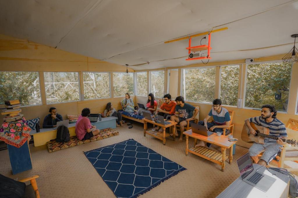 eine Gruppe von Menschen, die in einem Zimmer mit Laptops sitzen in der Unterkunft Mars Monkey Hostel & Cafe in Manali