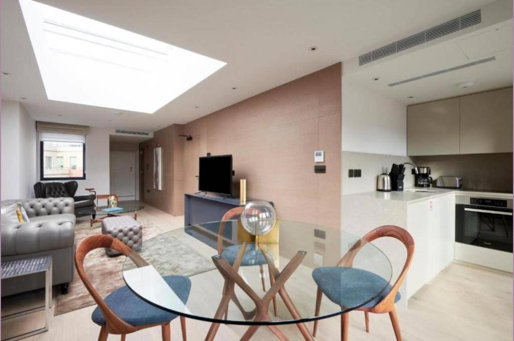 cocina y sala de estar con mesa de cristal y sillas en Maddox Street - 3 bed en Londres