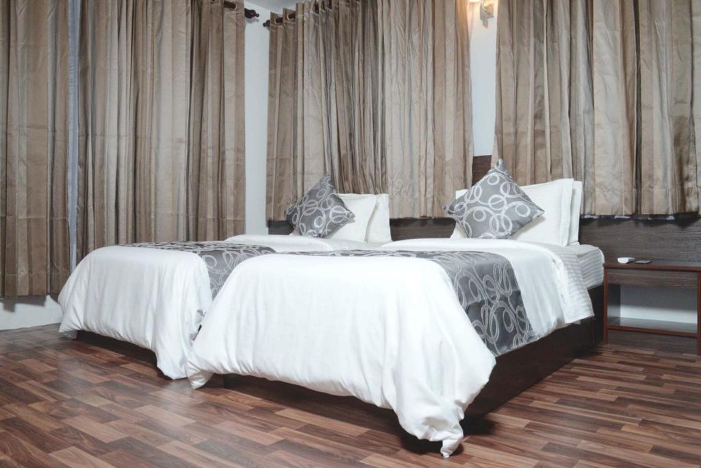2 bedden in een hotelkamer met witte en grijze lakens bij North Edge Inn in Kanditheemu